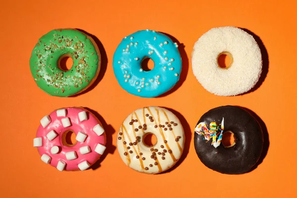 Diferentes Deliciosos Donuts Envidraçados Fundo Laranja Flat Lay — Fotografia de Stock