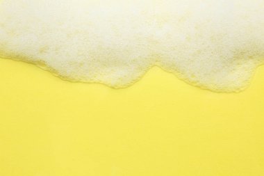 Sarı arka planda tüylü banyo köpüğü, üst manzara. Metin için boşluk