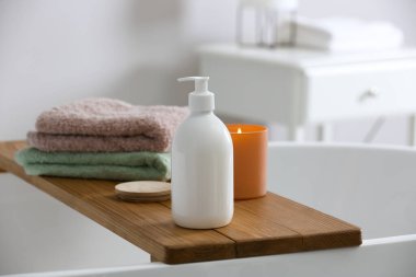Banyoda banyo köpüğü, havlu ve mum dolu tepsi.