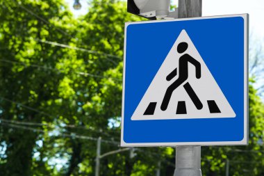 Güneşli bir günde yaya geçidi ile ağaçlara karşı trafik tabelasını geç