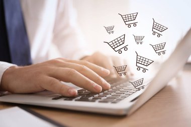 Bilgisayarı ahşap masada online alışveriş için kullanan adam, yakın plan.