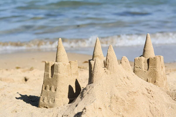 Beach with sand castle near sea on sunny day