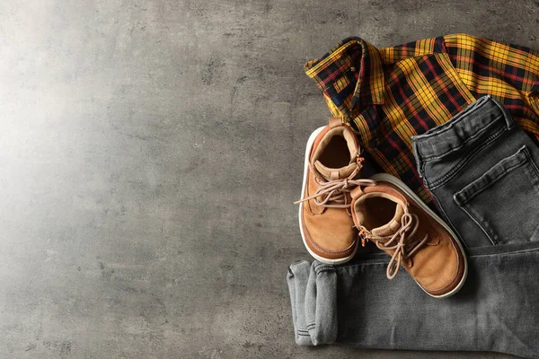Stylish child clothes and shoes on grey background, flat lay. Space for text