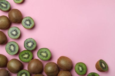 Birçok kesim ve taze olgun kivi pembe arka planda, düz yatıyordu. Metin için boşluk