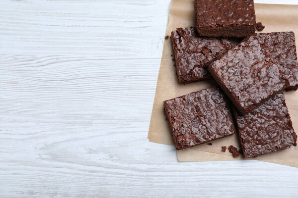Delicious chocolate brownies on white wooden table, top view. Space for text