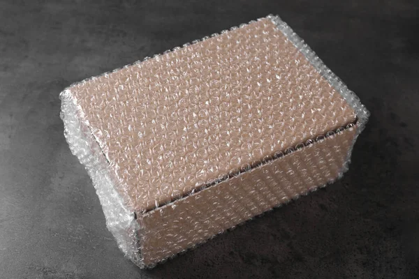 Caixa Papelão Coberta Com Plástico Bolha Mesa Cinza Escuro — Fotografia de Stock
