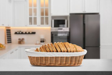 Mutfaktaki gri masada hasır sepette taze ekmek.