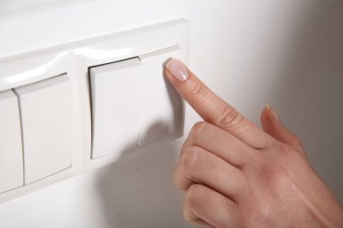 Kapalı mekanda ışığı kapatan kadın, yakın çekim. Enerji tasarrufu kavramı