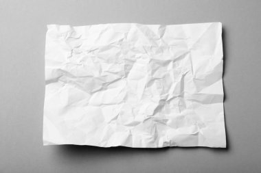 Gri arkaplan üzerine beyaz buruşuk kağıt yaprağı, üst görünüm