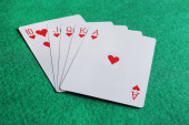 Hrací karty s královskou kombinací flush na zeleném stole