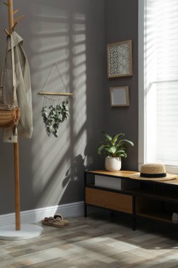 Koridordaki gri duvarda asılı kuru bambu çubuğu ve okaliptüs dallarından oluşan güzel bir dekor.