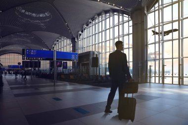 Havaalanının bekleme salonunda bavul ve çanta taşıyan bir iş adamı.