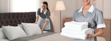 Otel odasında bir yığın temiz havlusu olan oda hizmetçisi, mesaj için yeri olan yakın çekim manzarası. Pankart tasarımı
