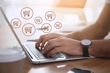 Bilgisayarı ahşap masada online alışveriş için kullanan adam, yakın plan.