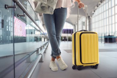 Havaalanı terminalinde sarı valizli kadın, yakın çekim görüntüsü.