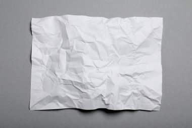 Gri arkaplan üzerine beyaz buruşuk kağıt yaprağı, üst görünüm