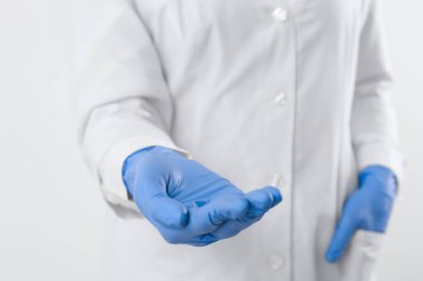 Doktor beyaz arka planda bir şey tutuyor, yakın plan.