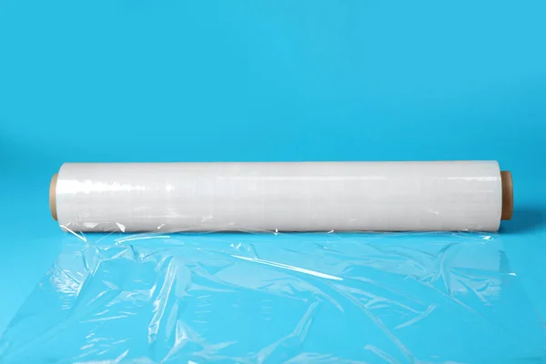 Roll of transparent stretch wrap on turquoise background