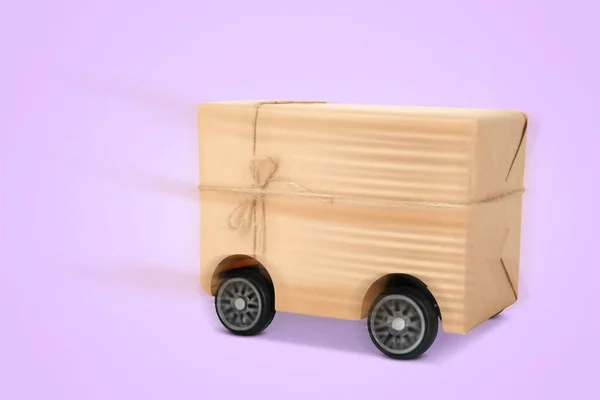 淡い紫色の背景に車輪のギフトボックス 依頼人に急いで注文する 配達サービス — ストック写真