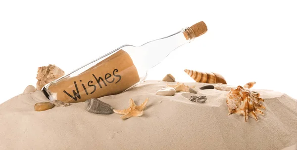 Corked glass bottle with Wishes note and seashells on sand against white background