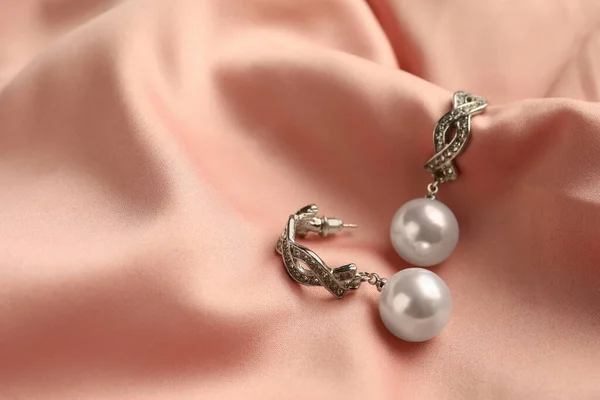 ピンクの絹の上に真珠とエレガントな銀のイヤリング クローズアップ — ストック写真
