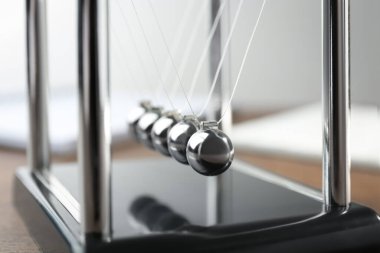 Newton 'un beşiği ahşap masada, yakın plan. Enerji korunumunun fizik yasası