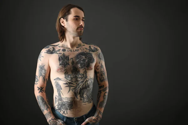 Young man with tattoos on body against black background. Space for text