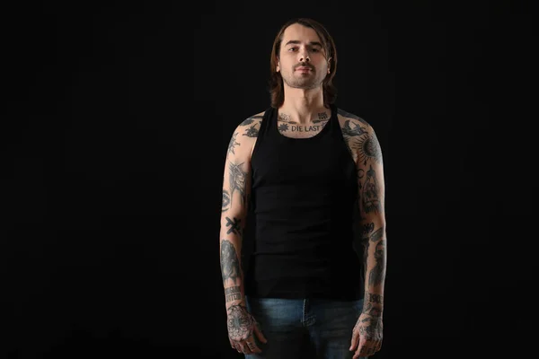 Young man with tattoos on body against black background