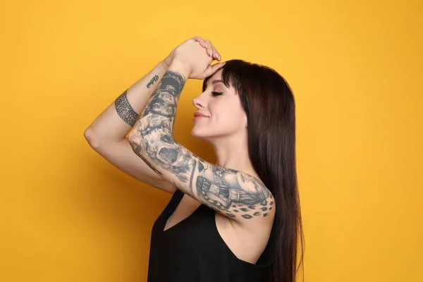 Mulher Bonita Com Tatuagens Nos Braços Contra Fundo Amarelo — Fotografia de Stock