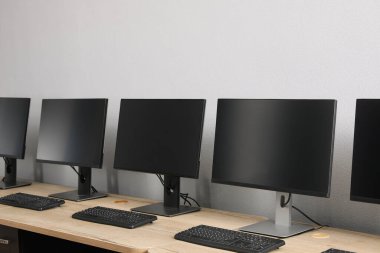 Ofisin içini aç. Açık gri duvarın yanında bilgisayarları olan modern işyerleri