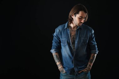 Siyah arka planda dövmeleri olan genç bir adam. Metin için boşluk