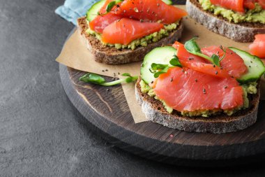 Somonlu lezzetli bruschettalar, guacamole ve mikroyeşiller siyah masada, yakın plan.