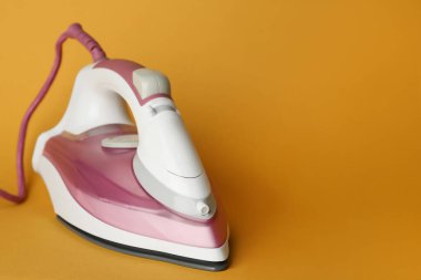 Turuncu arka planda modern bir ütü, metin için boşluk. Ev aletleri