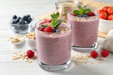 Beyaz ahşap masada çilekli, nane ve yulaf ezmeli leziz bir smoothie.