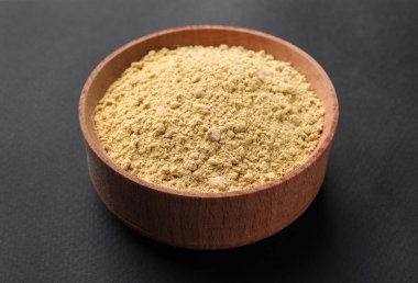 Koyu arkaplanda ahşap kasede Aromatik hardal tozu