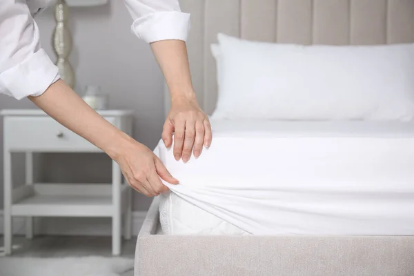 ベッドの上のマットレスの上に白いフィットシートを置く女性屋内 クローズアップ — ストック写真