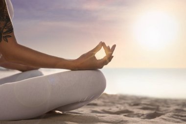 Gün doğumunda sahilde meditasyon yapan genç bir kadın, yakın plan. Yoga çalışıyorum.