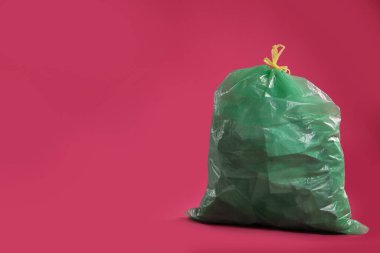 Pembe arka planda çöp dolu bir çöp torbası. Metin için boşluk