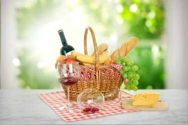 Piknik sepeti, içinde yiyecek ve şarap bardakları olan beyaz mermer masa.