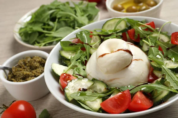 Delicious burrata salad and ingredients on wooden table
