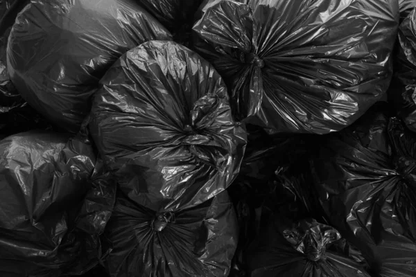 Black trash bags full of garbage as background, top view