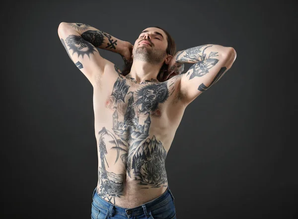 Young man with tattoos on body against black background