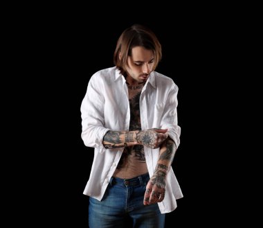 Siyah arka planda dövmeleri olan genç bir adam.