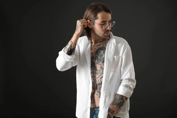 Young man with tattoos on body against black background