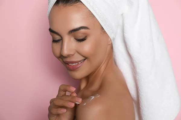 Mooie Jonge Vrouw Met Handdoek Aanbrengen Crème Schouder Tegen Roze — Stockfoto