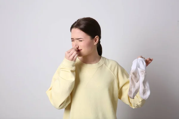 Young Woman Feeling Bad Smell Dirty Socks Light Grey Background — Fotografia de Stock