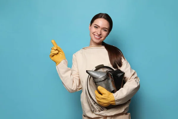 Apicoltore Uniforme Con Fumogeno Che Punta Qualcosa Sfondo Azzurro — Foto Stock