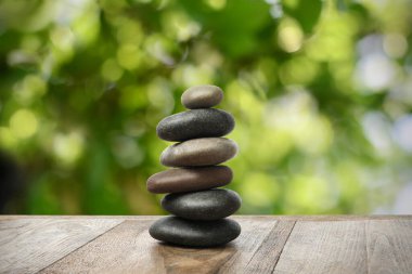 Ahşap masaya istiflenmiş taşlar, bulanık arka plana karşı. Zen kavramı