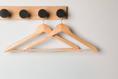 Boş ahşap elbiseli raflar beyaz duvarda asılı.