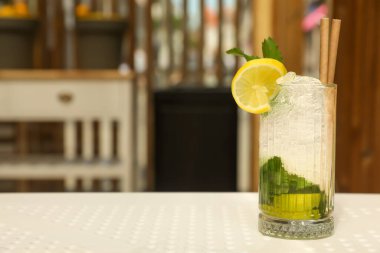 Bir bardak ferahlatıcı narenciye içeceği beyaz masa içinde, mesaj için yer var.